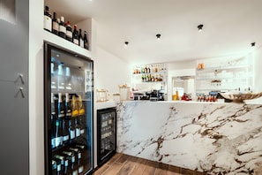 Eine moderne Bar mit einem Weinkühlschrank, Flaschenregalen und einer Marmorarbeitsplatte.