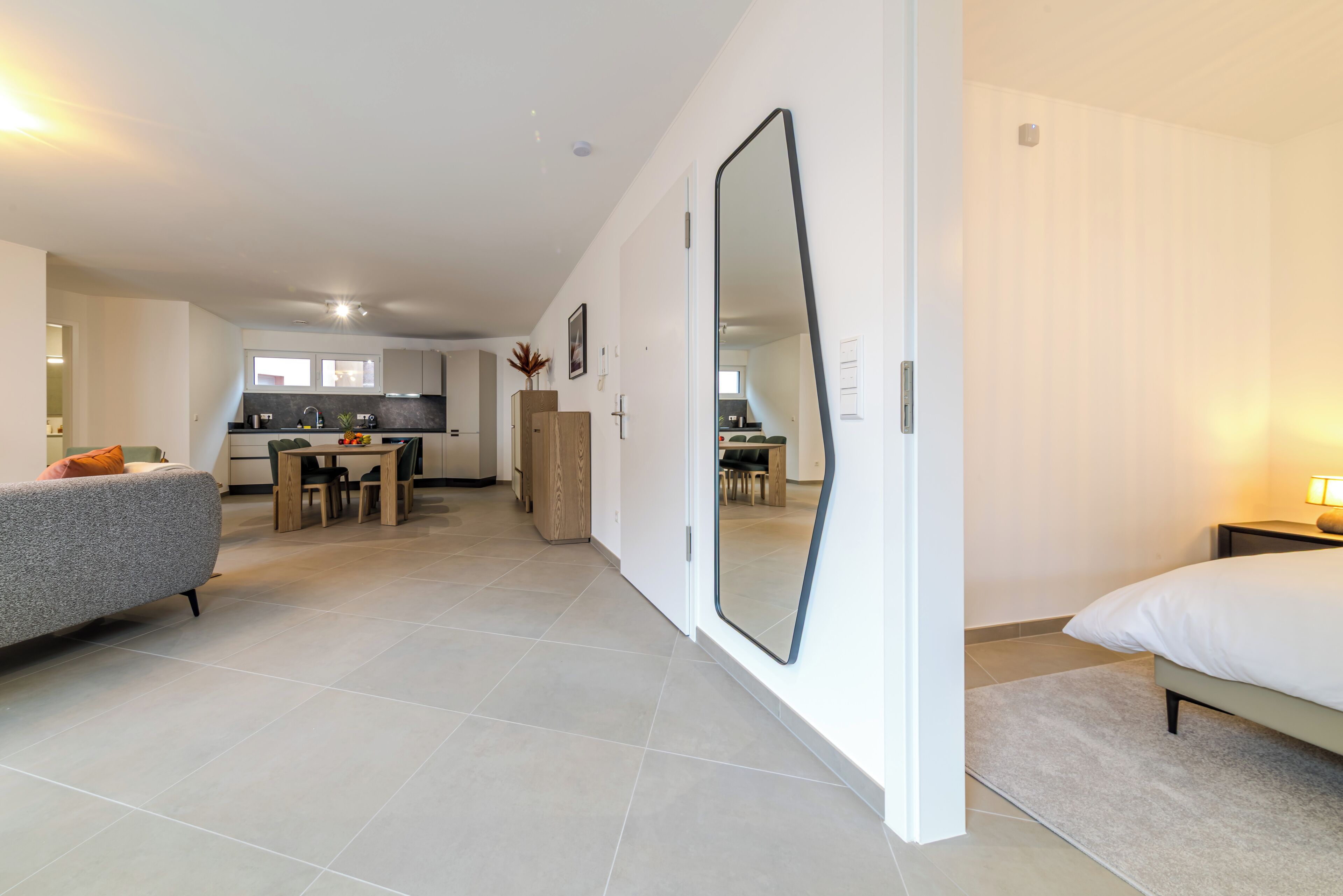 A modern apartment with a kitchen, dining area, and a large mirror.