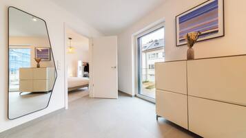 Una habitación de hotel moderna con un espejo grande, una cama, un armario y una ventana con vistas al exterior.