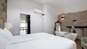 A hotel room with a large bed, a vanity with a mirror, a bathtub, and a patterned chair. - 'Piazzetta' Apartment with Balcony, Wi-Fi and Air Conditioning (Gardola)