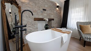 A modern bathroom with a freestanding bathtub, a large mirror with an ornate frame, and a stone wall. - 'Piazzetta' Apartment with Balcony, Wi-Fi and Air Conditioning (Gardola)
