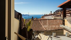 A terrace with a view of the sea, a potted plant, and a tiled roof. - 'Piazzetta' Apartment with Balcony, Wi-Fi and Air Conditioning (Gardola)