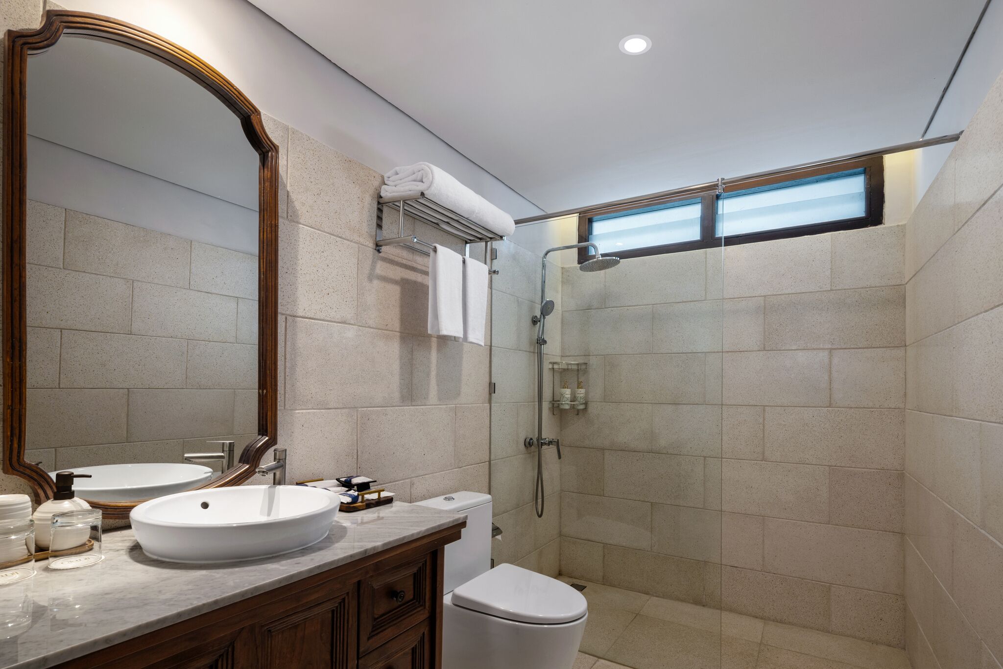 A modern bathroom with a large mirror, a sink, a toilet, and a shower.