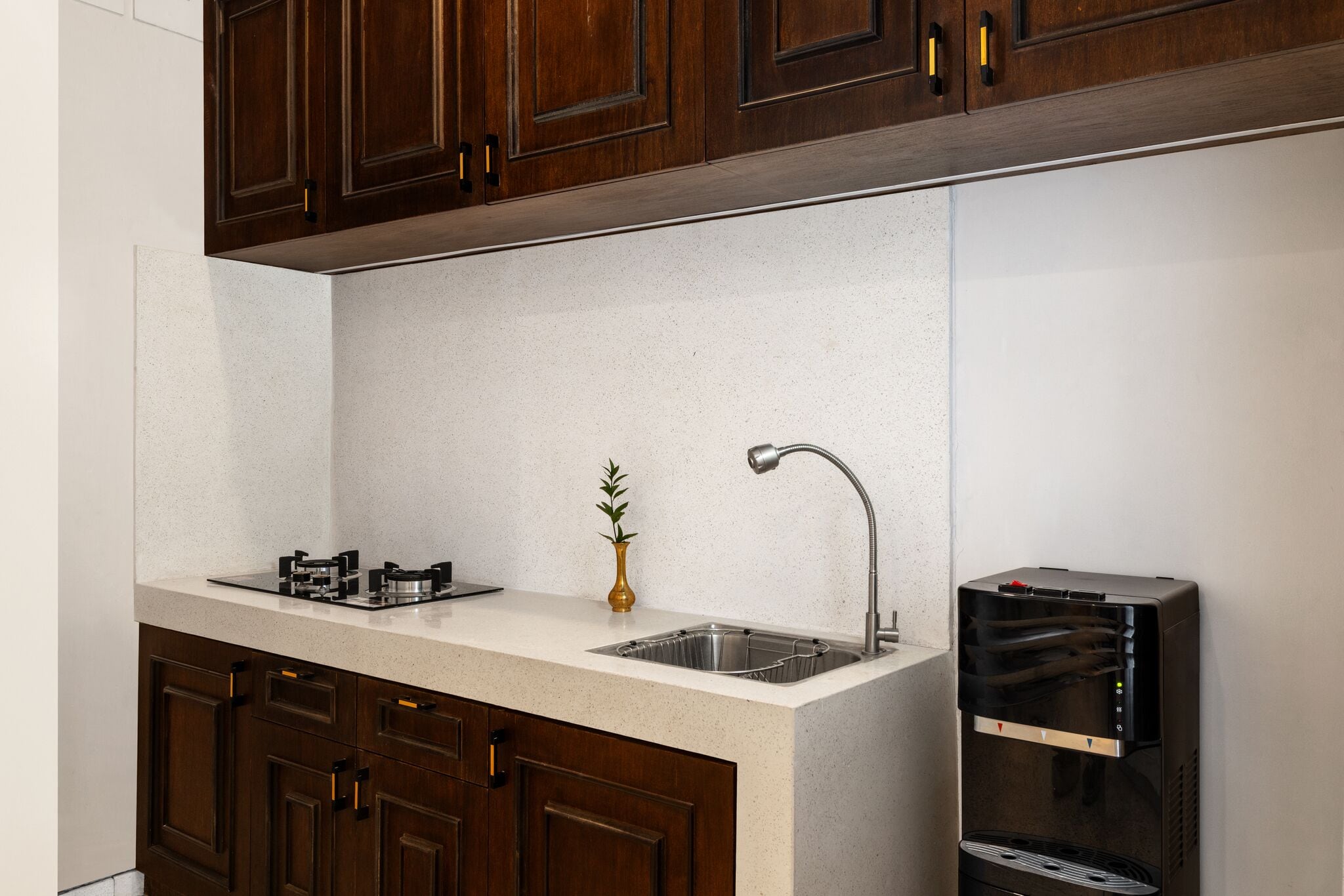 Una cocina con un lavamanos de acero inoxidable, horno empotrado y armarios de madera.