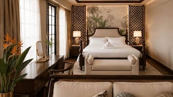 A hotel room with a large bed, bedside lamps, a desk with a mirror, and a potted plant.