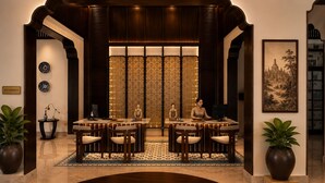 A reception area with a reception desk, two chairs, a large window with patterned curtains, and a framed picture on the wall. - The Prajan Hotel & Villas by Natt's (Yogyakarta)