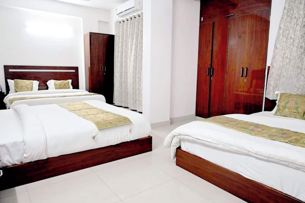 Een hotelkamer met twee bedden, houten kasten en een groot raam met gordijnen.