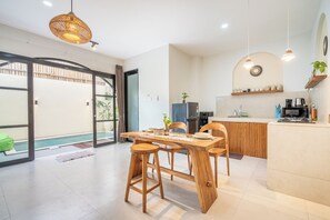 Cozinha moderna com ilha de madeira, banquetas e iluminação pendente.