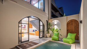 Ein moderner Poolbereich mit Holzterrasse, einem grünen Stuhl und einer Holztür.