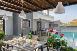 Ein Essbereich mit gedecktem Tisch für das Frühstück, mit Blick auf einen Pool und ein modernes Gebäude.