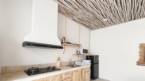 A kitchen with wooden cabinets, a gas stove, a microwave, and a black refrigerator. - Suilaya Villa Uluwatu (Pecatu)