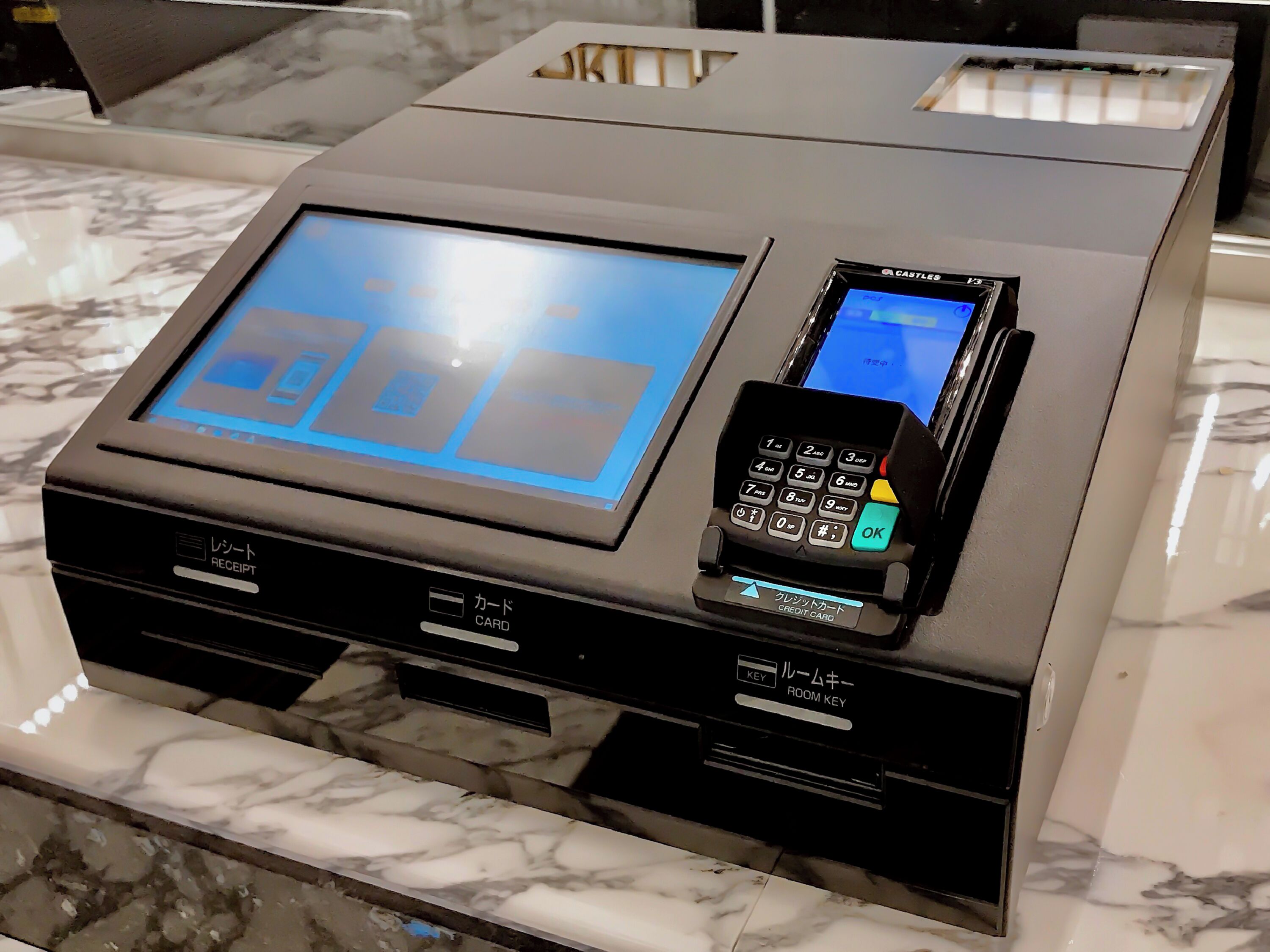 A hotel reception desk with a digital display, a card reader, and a room key station.