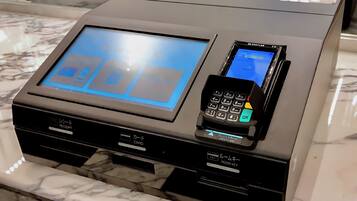 A hotel reception desk with a digital display, a card reader, and a room key station.