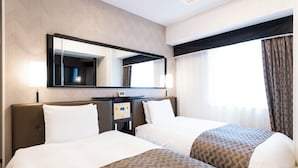 Una camera d'albergo con due letti, uno specchio grande, un pannello di controllo e una finestra con tende.