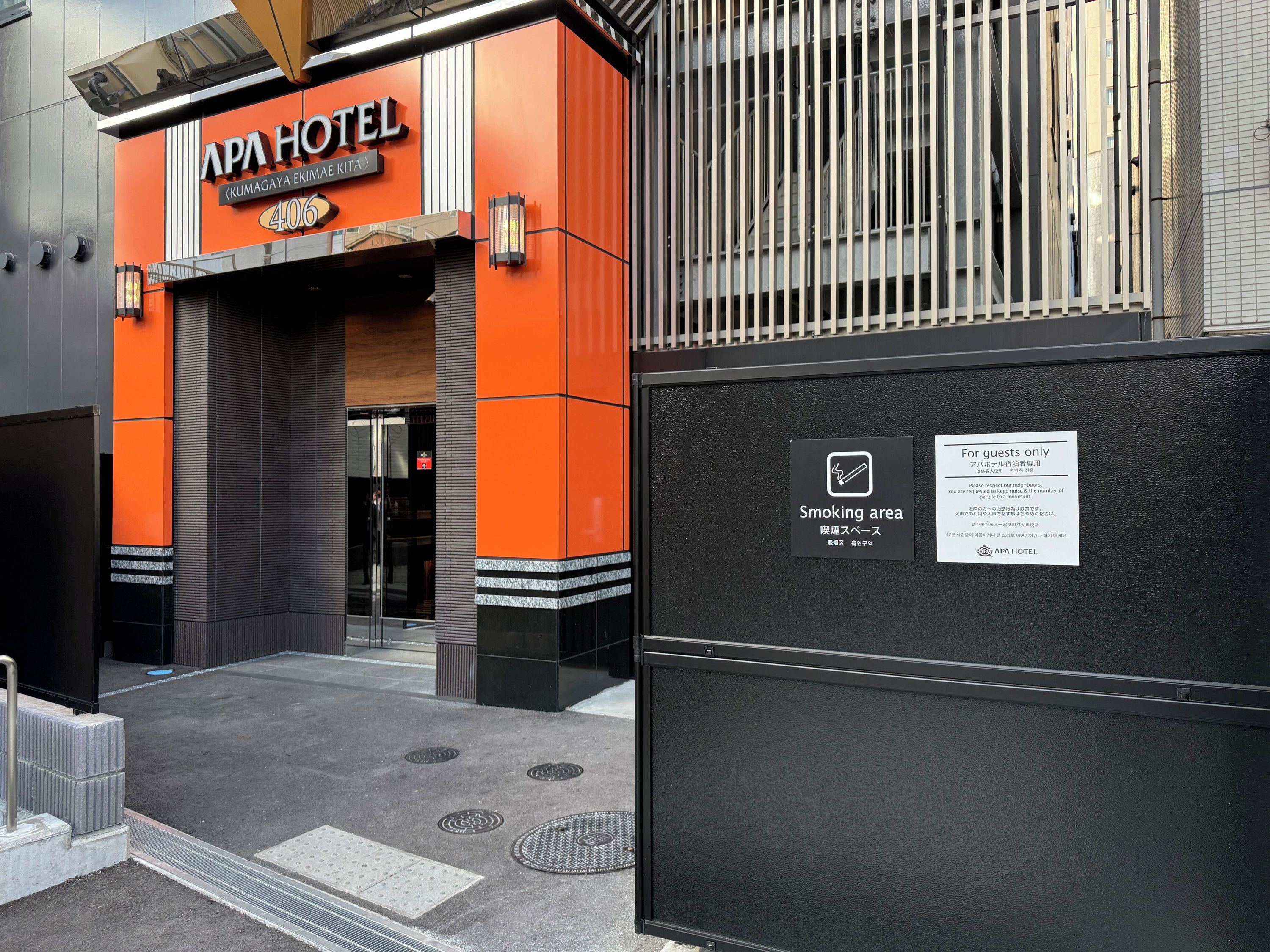 La entrada del APA HOTEL con un cartel que indica una zona para fumadores.