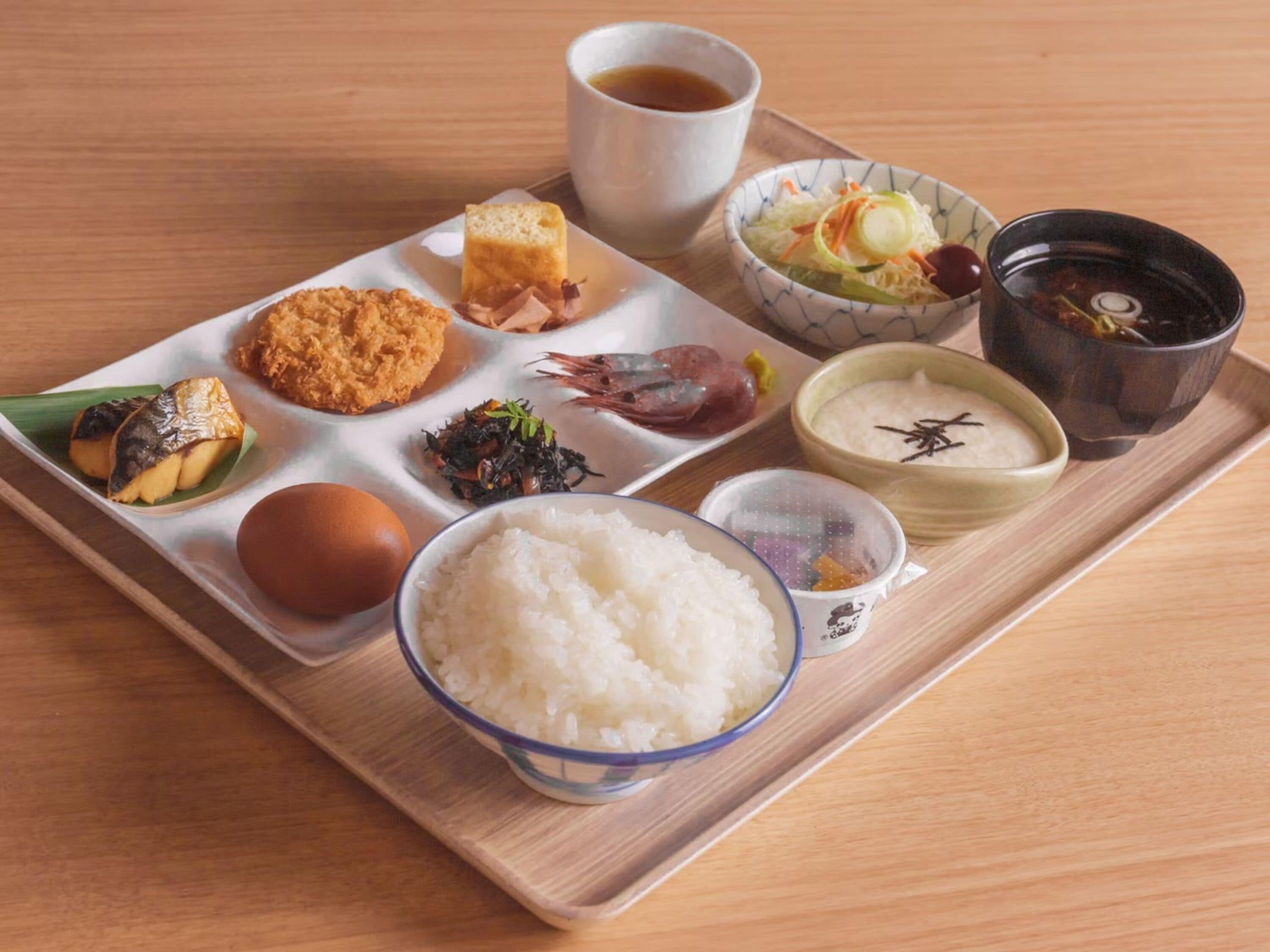 Una bandeja con diversos platos japoneses, incluyendo arroz, pescado y verduras.