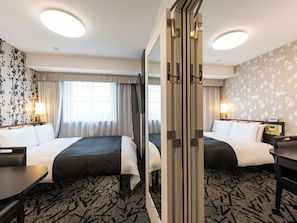 A hotel room with two beds, a desk, a mirror, and a nightstand with a lamp.