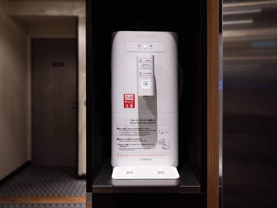 Un distributore di acqua con istruzioni in diverse lingue, posizionato su un tavolo in una camera d'albergo.