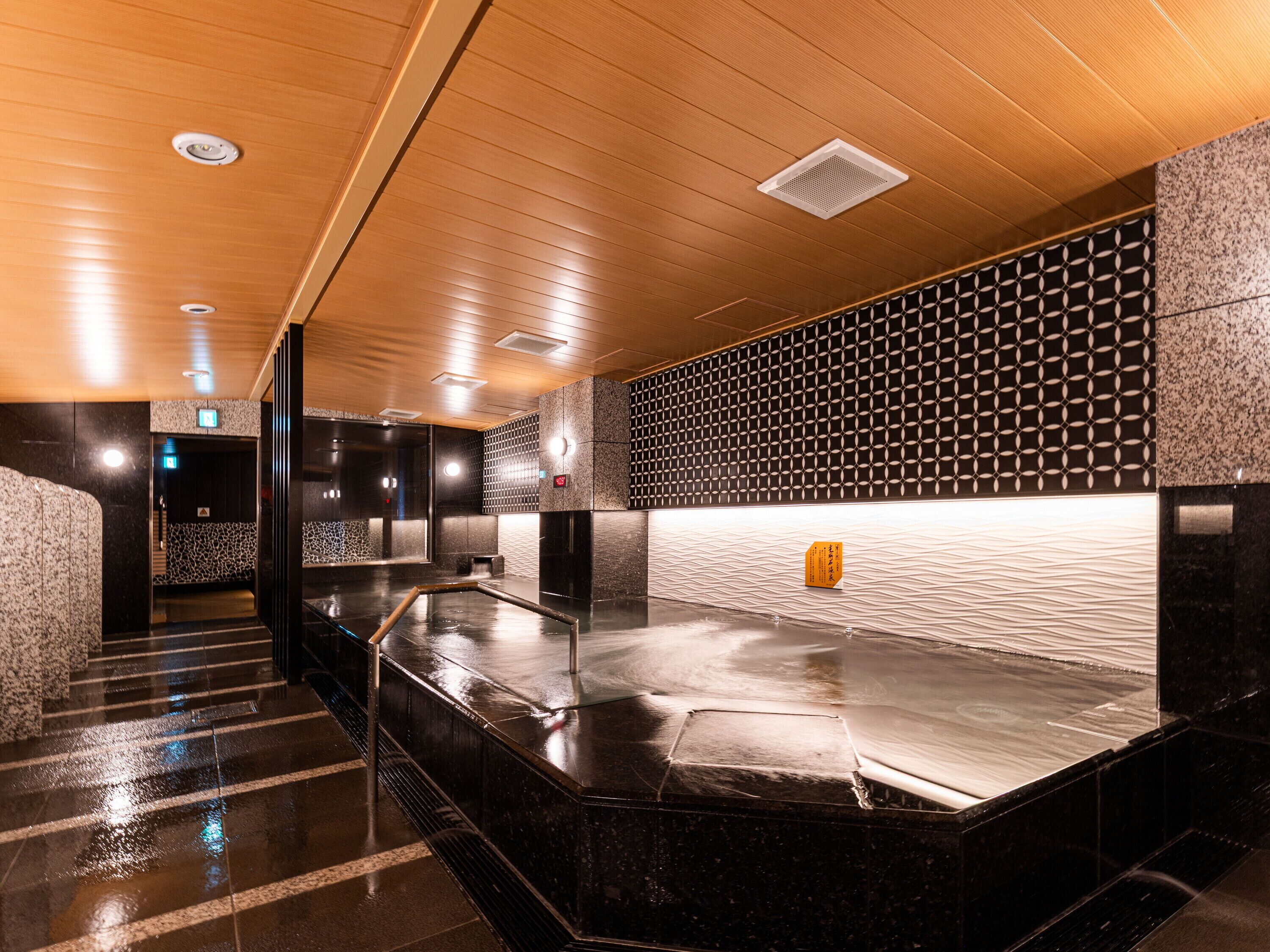 A modern hotel lobby with a wet floor, a reception desk, and a patterned wall.