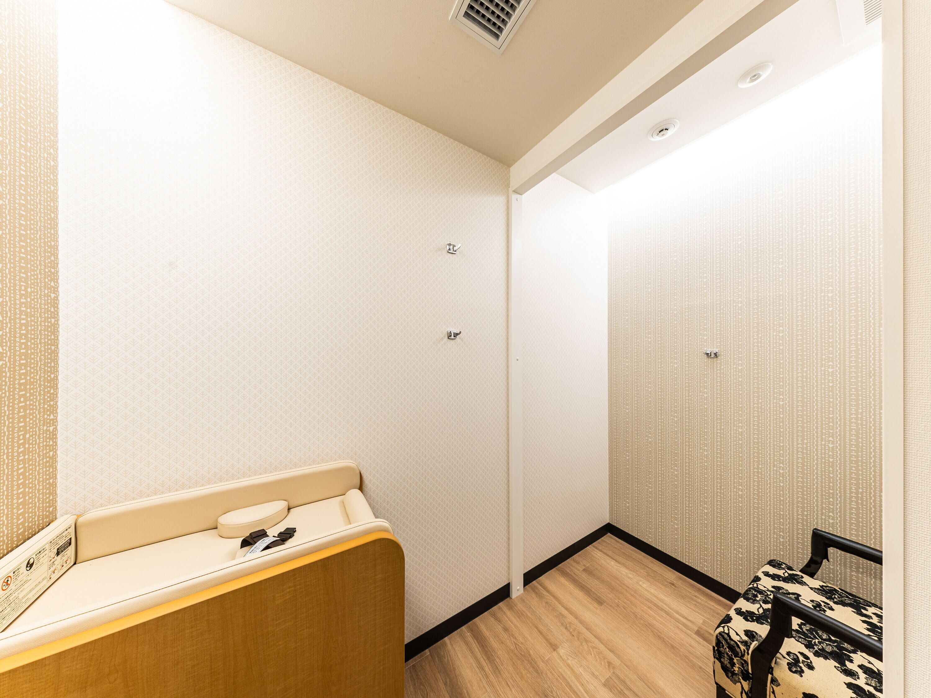 A hotel room with a wooden bench, a small table, and a patterned wall.