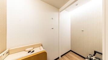 A hotel room with a wooden bench, a small table, and a patterned wall.