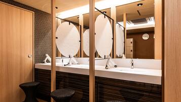 Une salle de bain moderne avec deux lavabos, des miroirs et des tabourets noirs.