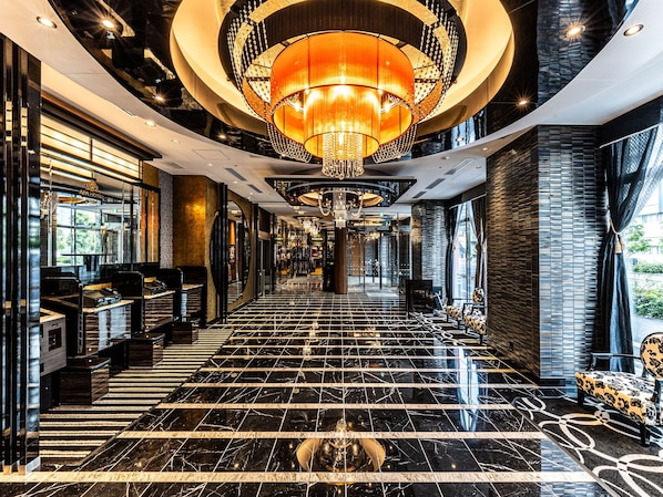 Eine Hotelhalle mit einer Kandelaber, Marmorböden und einer Sitzecke mit einem gemusterten Teppich.