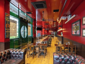 Ein Pub-Interieur mit Holztischen, Ledersitzbänken und einem Billardtisch.