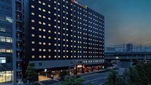 A modern hotel building with a flat facade, numerous windows, and a visible entrance with a parking sign. - APA Hotel Saitama-Shintoshin Ekinishi (Saitama)