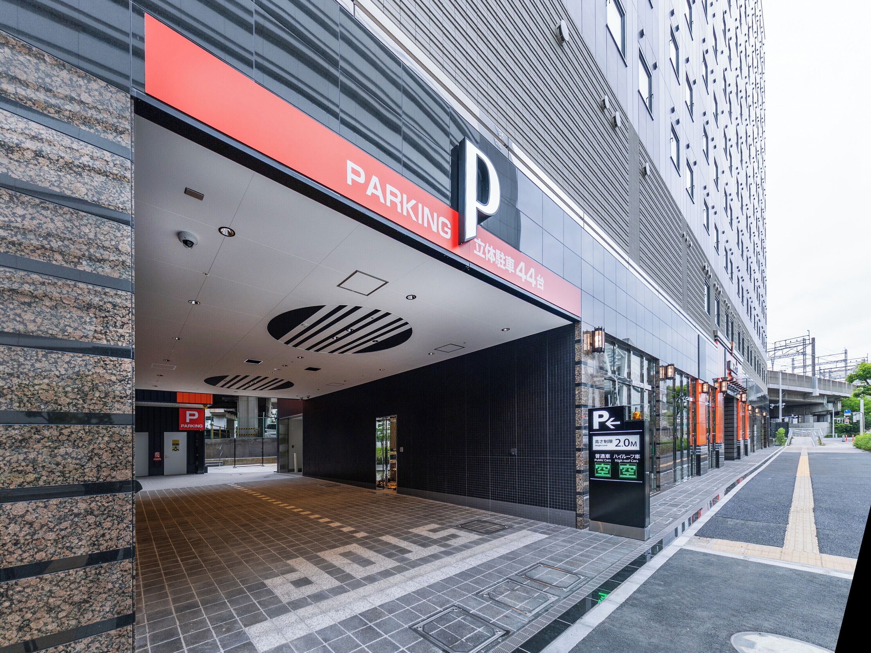 A modern building with a prominent 'PARKING' sign, a covered entrance, and a clear pathway leading to the entrance.