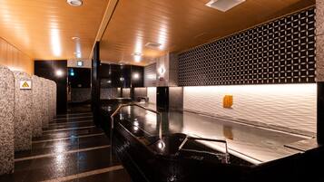 A modern bathroom with a wet floor, a black sink, and a textured wall.