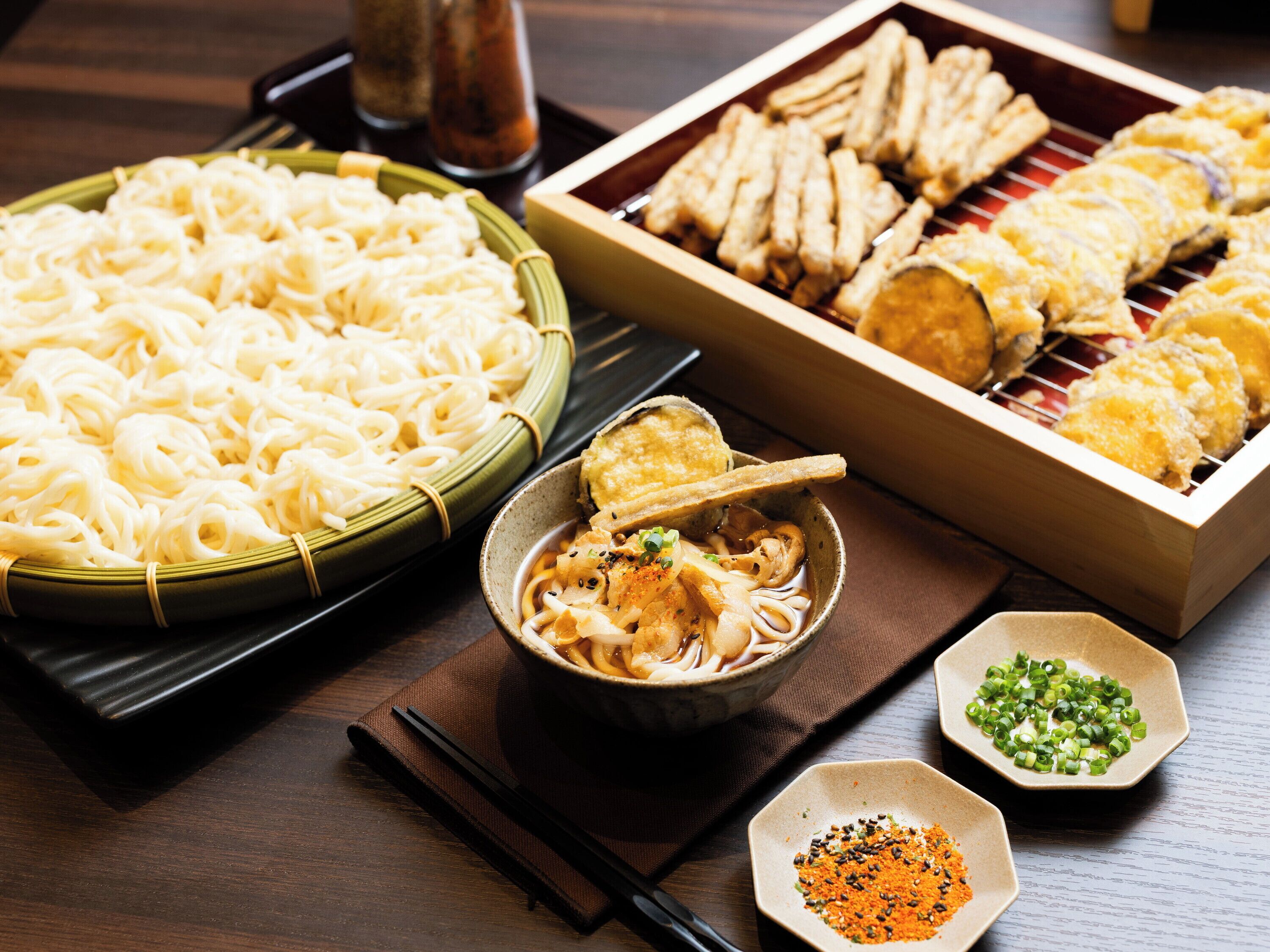 Variedad de platos japoneses, como fideos, tempura y un tazón de sopa.