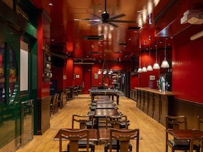 Ein Restaurant mit Holztischen und -stühlen, einer Poolbillardkugel und einem Deckenventilator.