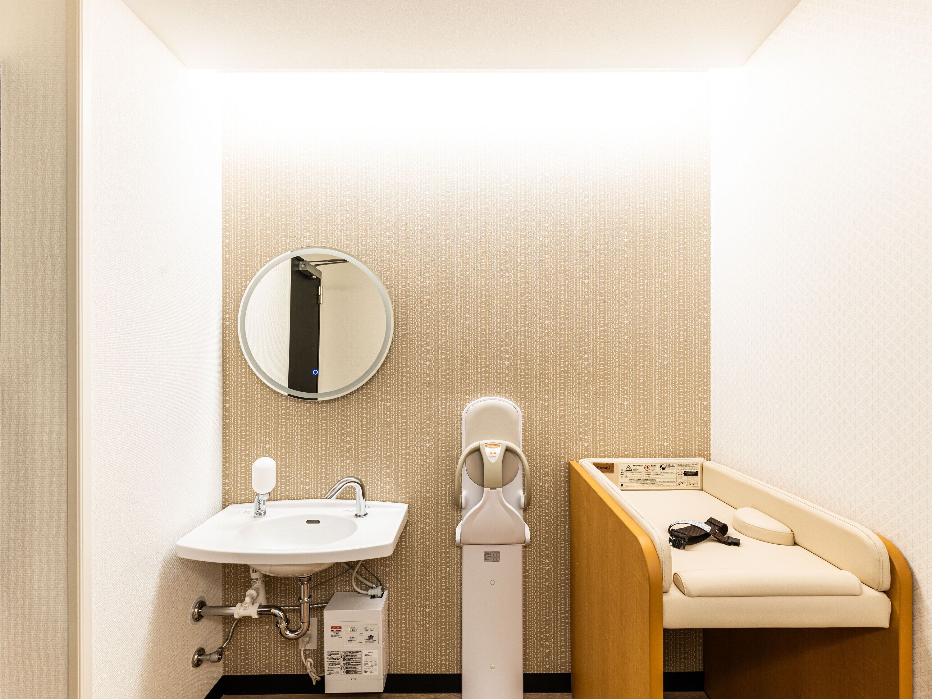 Ein Badezimmer mit Waschbecken, Spiegel, Toilette und einer Bank.