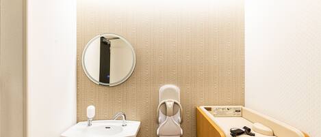 Ein Badezimmer mit Waschbecken, Spiegel, Toilette und einer Bank.