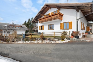 A two-story building with a balcony, a stone wall, and potted plants.