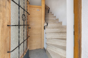 A wooden door with a metal gate, a staircase with beige steps, and a white wall.