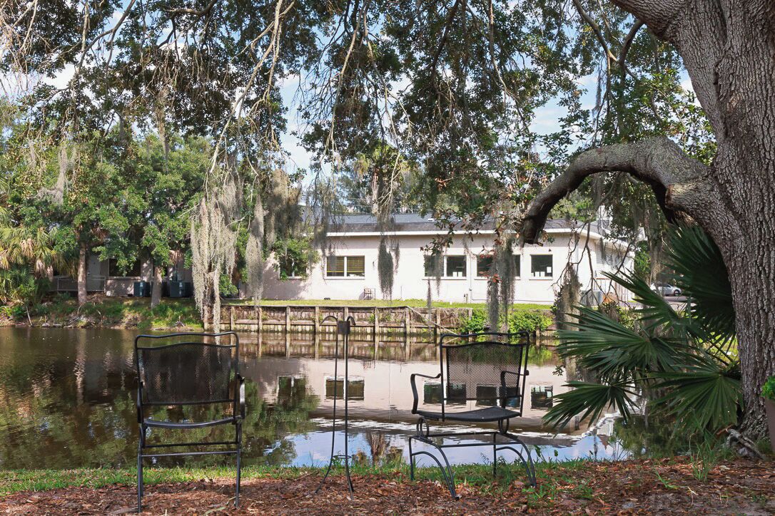 Un parc paisible avec un étang, des bancs et un bâtiment en arrière-plan.