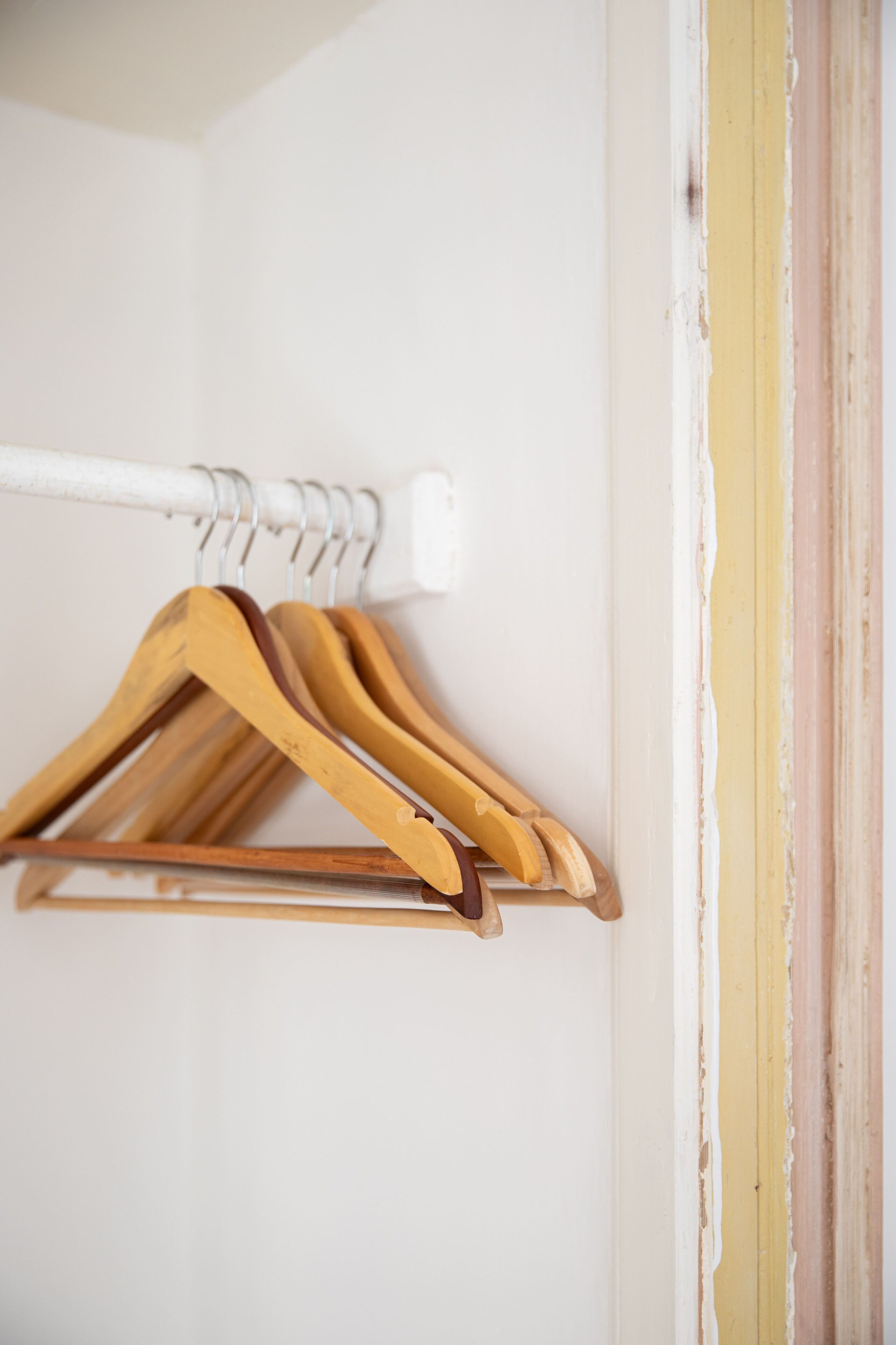 A white wall with a wooden coat rack holding several wooden hangers.