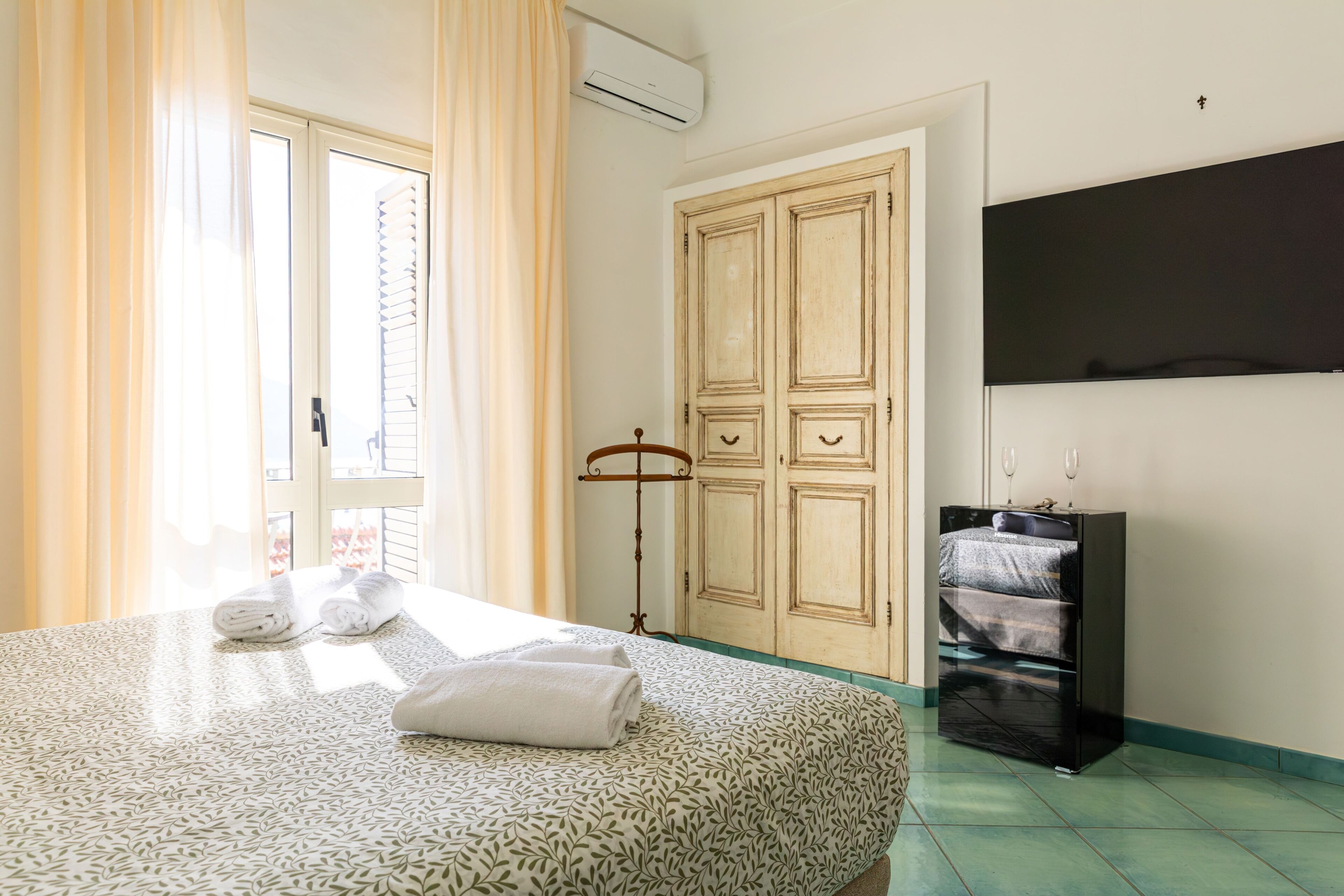 A bedroom with a bed, a wardrobe, a television, and a radiator.