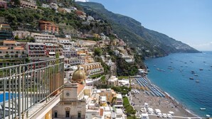 A coastal town with buildings along the hillside, a beach with umbrellas, and boats in the water. - Hotiday Positano Sea View (Positano)