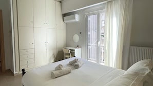 Un dormitorio con una cama grande, un armario, un escritorio y una ventana con cortinas.