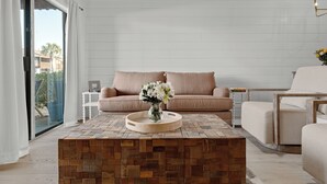 En moderne stue med et træbord, en beige sofa og en glasdør, der fører ud til en balkon.