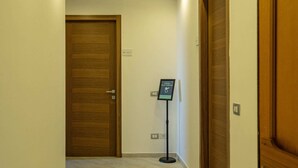 Un pasillo con puertas de madera, un atril con señalizaciones e iluminación empotrada en el techo.