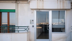 Un edificio con puerta de cristal que indica '21', barandilla de metal y vista de la ciudad a través de las ventanas.