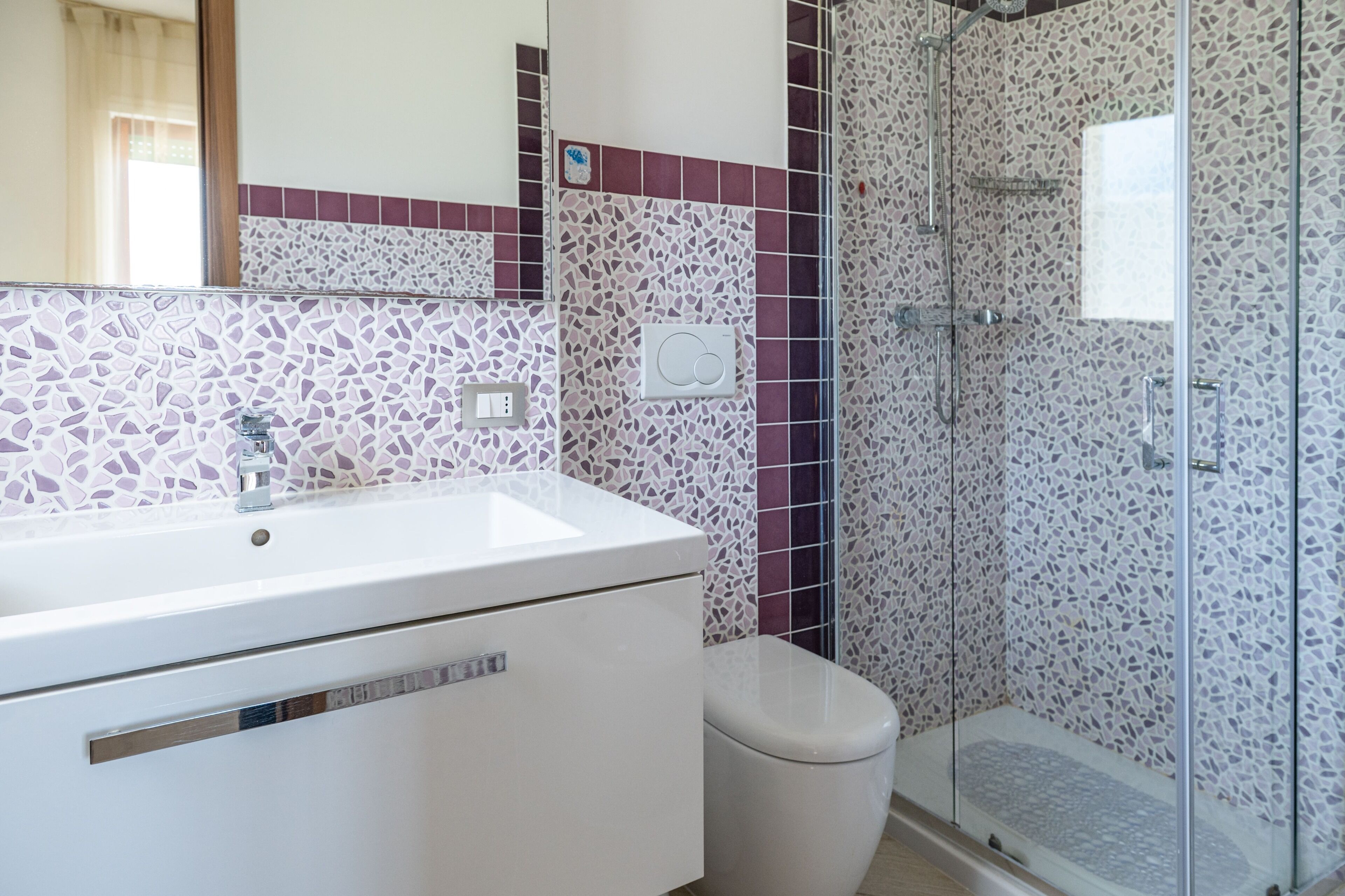 A bathroom with a white sink, a toilet, and a glass shower enclosure.
