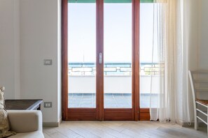 A room with a sliding glass door leading to a balcony with a view of the sea. - Hotiday Gallipoli Lungomare (Gallipoli)