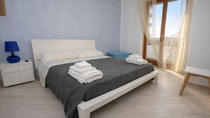 Un dormitorio moderno con cama, mesitas de noche y vistas al exterior.