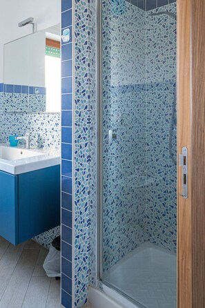 Een badkamer met een douche, een wastafel en een spiegel.