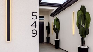 A modern building exterior with a large number '549' on the wall, large potted plants, and a skylight. - The Mustang Collection 49 Newly Built Desert Retreat (Page)